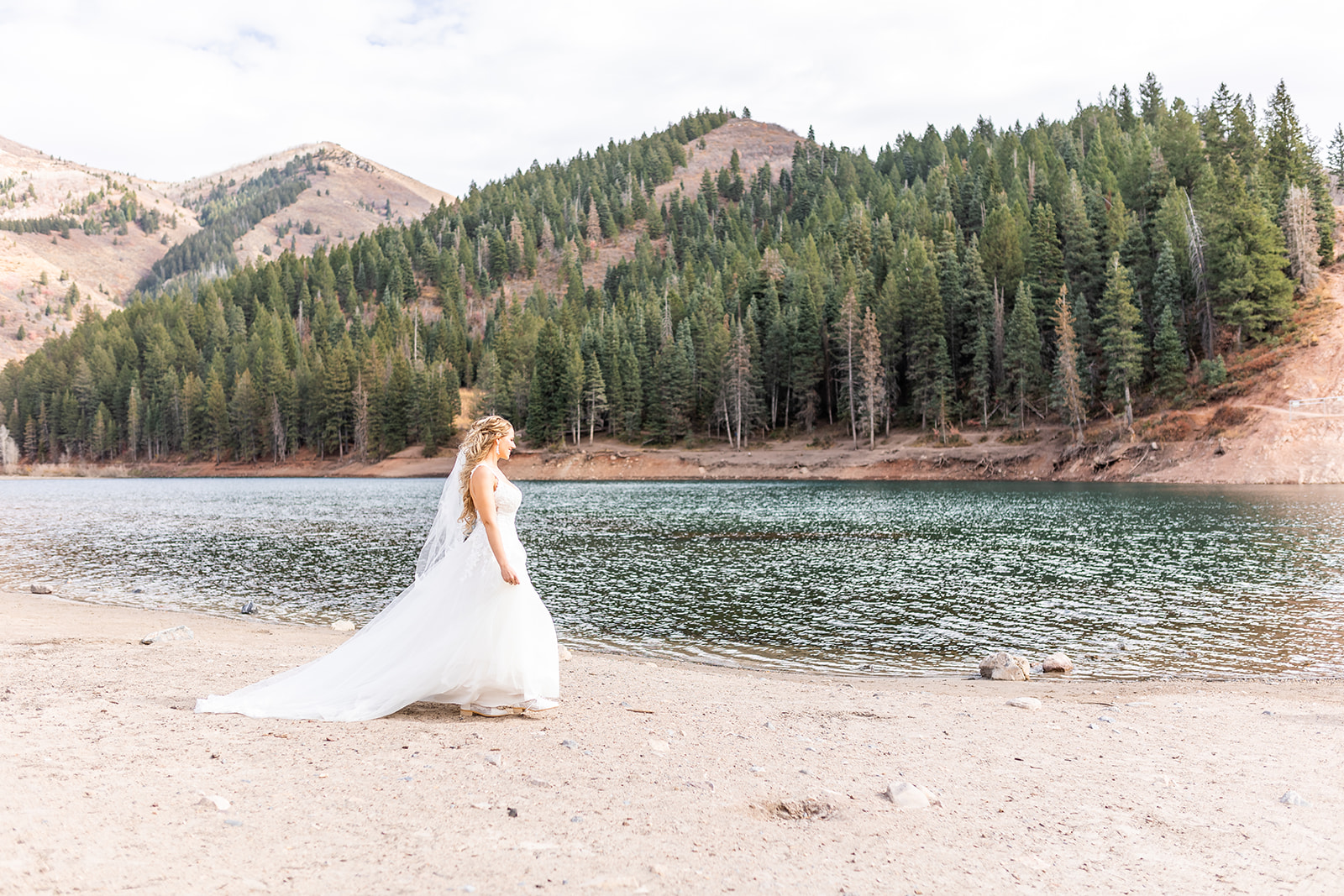 bride on the river bank with mountains in the background