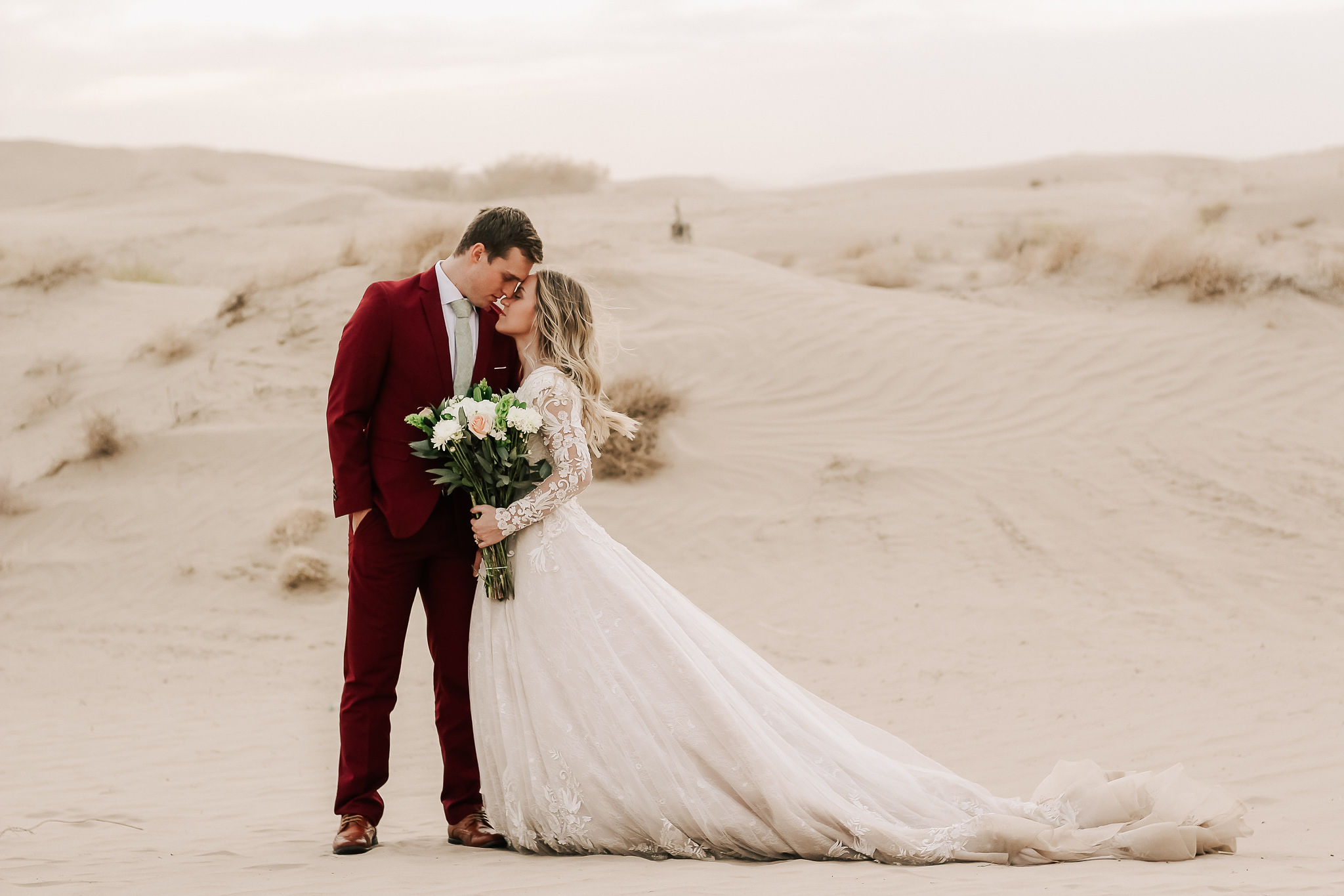 groom in velvet suit with bride in lace wedding dress in utah desert