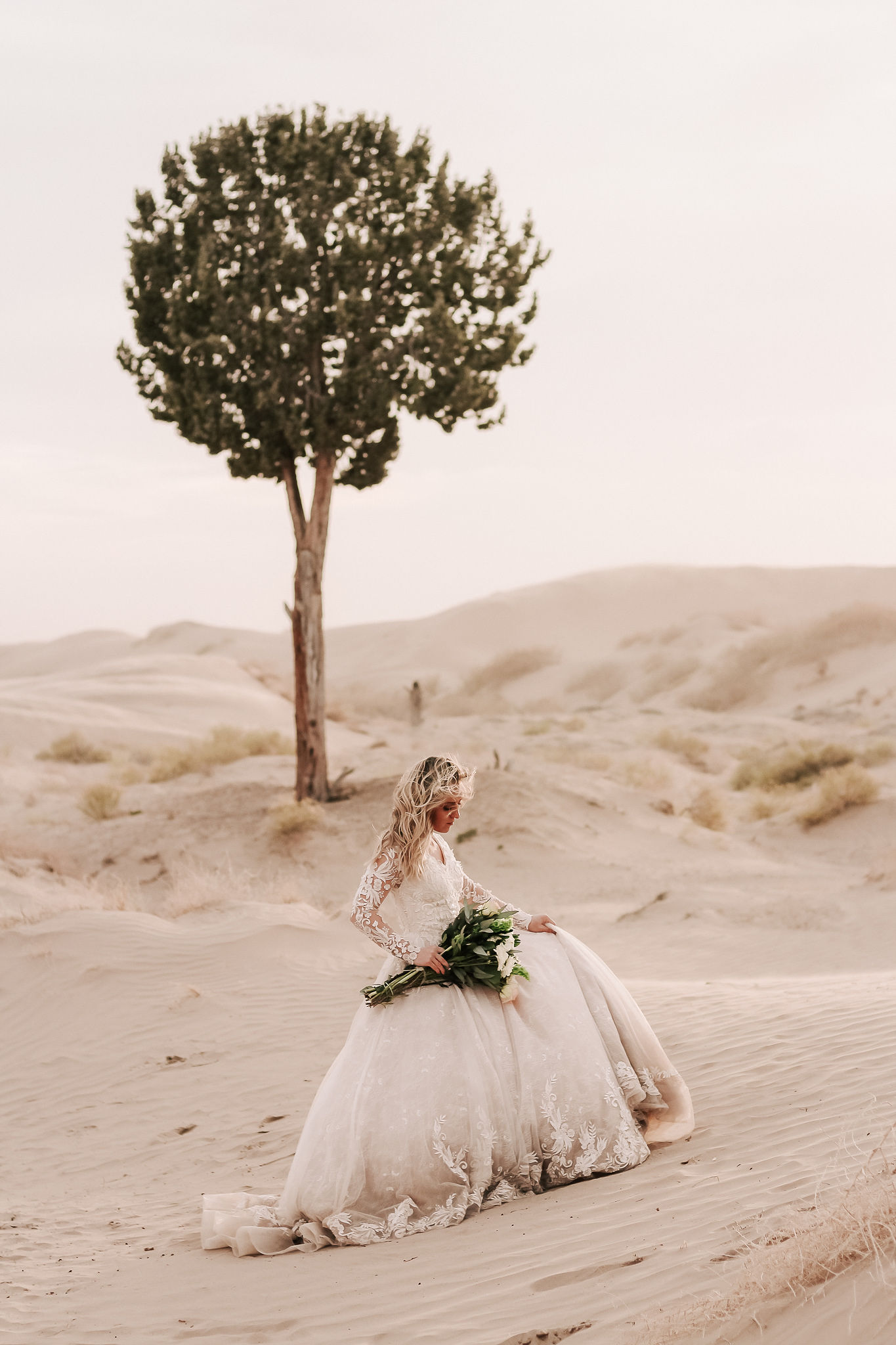 bride with wedding lace dress holding bouquet in utah desert