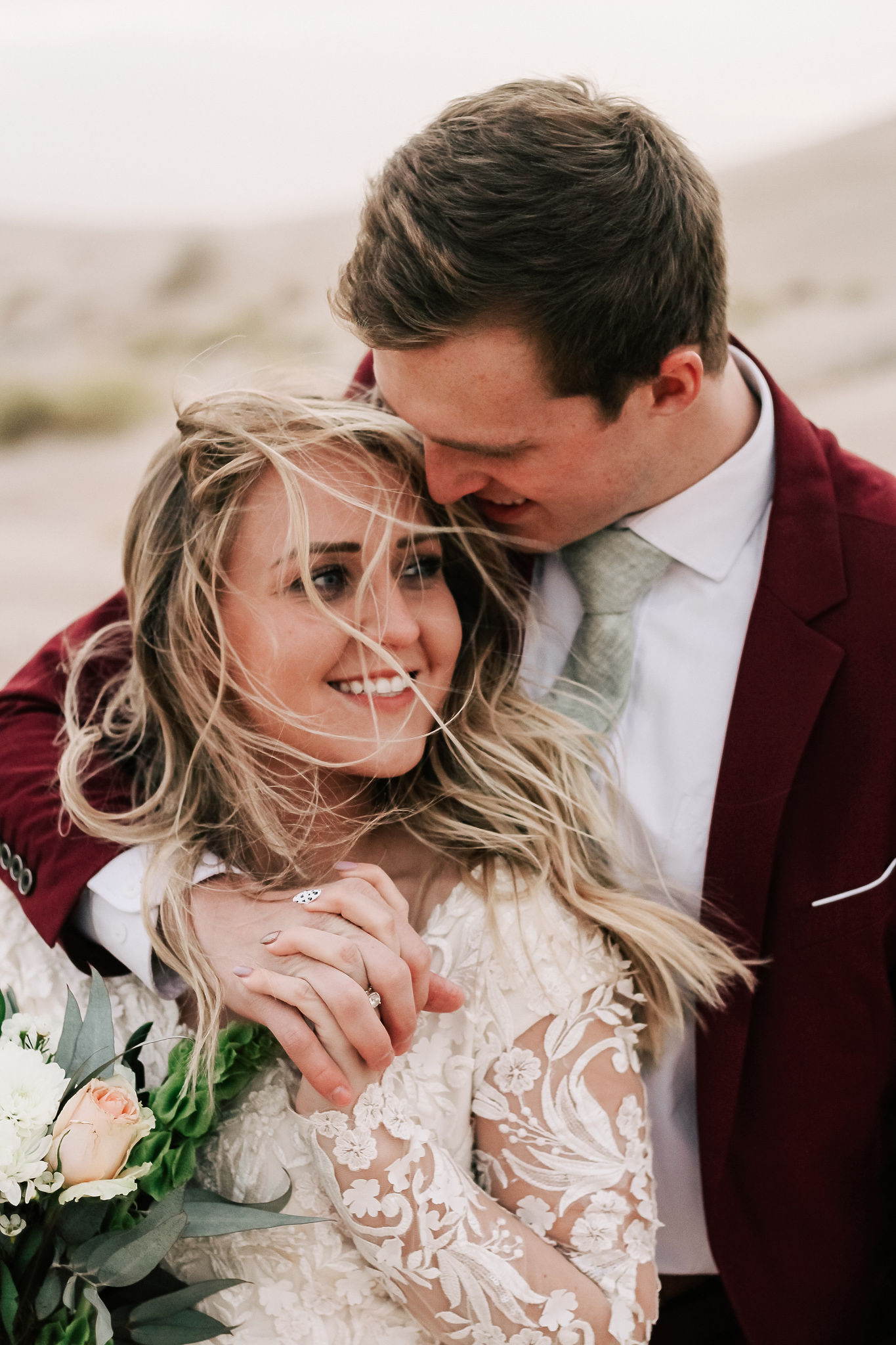 groom in velvet suit with bride in lace wedding dress in utah desert